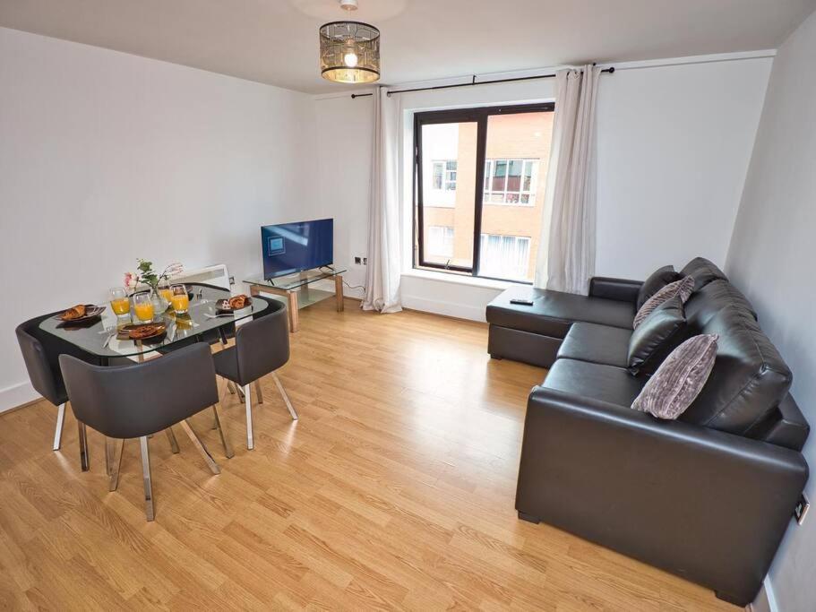 ein Wohnzimmer mit einem schwarzen Ledersofa und einem Tisch in der Unterkunft Lovely 1 Bedroom Apartment - Bham City Centre in Birmingham