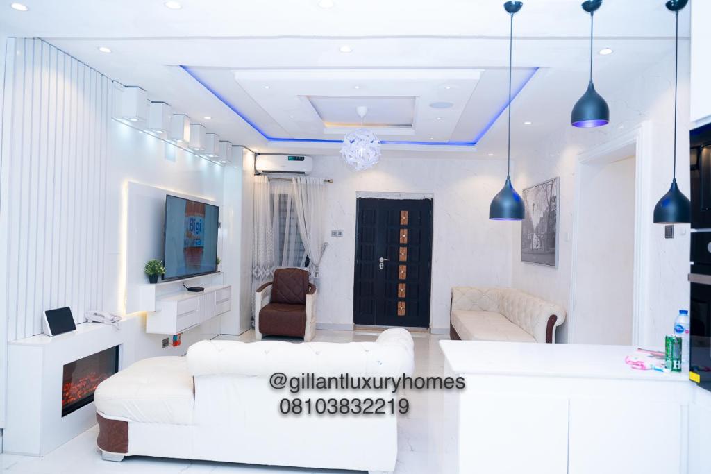 uma sala de estar com mobiliário branco e uma televisão em Gillant Luxury Homes em Benin City