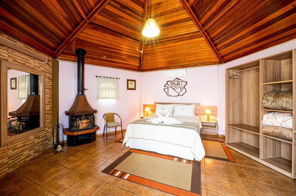 Un dormitorio con una cama y una chimenea. en Pousada Villa Da Montanha, en São Bento do Sapucaí