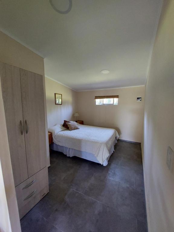 Un dormitorio con una cama blanca y una ventana. en Cabañas Casa fuerte, en San Rafael
