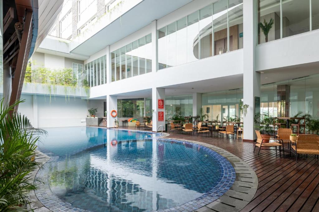 uma piscina interior num edifício com mesas e cadeiras em Antero Hotel Jababeka em Cikarang