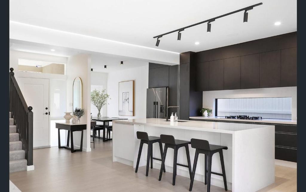 a kitchen with a white counter and black cabinets at Central Coast - Luxurious Beach House 400m to Beach in Bateau Bay