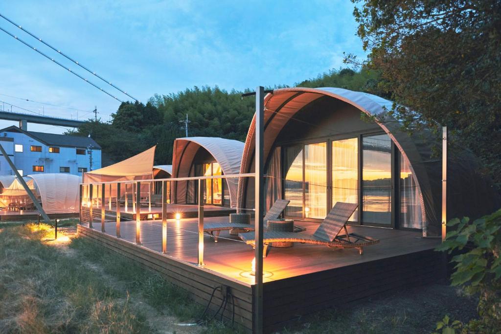 a pod house with two chairs on a deck at Glamprook Shimanami in Imabari