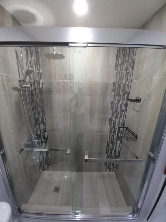 una ducha con puerta de cristal en un baño en K&S luxury apartments, en Montego Bay