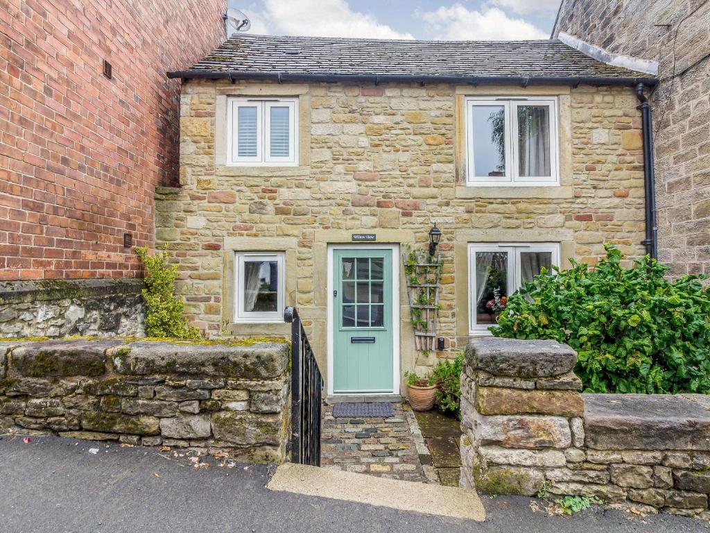 an old stone house with a blue door at Willow View in Stony Middleton