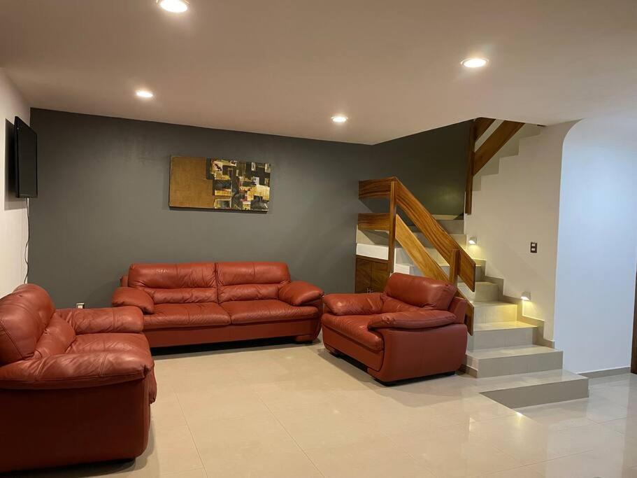 una sala de estar con muebles de cuero y una escalera. en Casa amplia con acceso a alberca., en San Agustín