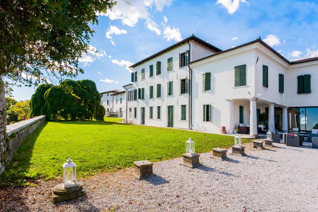 a large white building with a grassy yard in front at Hotel Villa Policreti in Castello dʼAviano