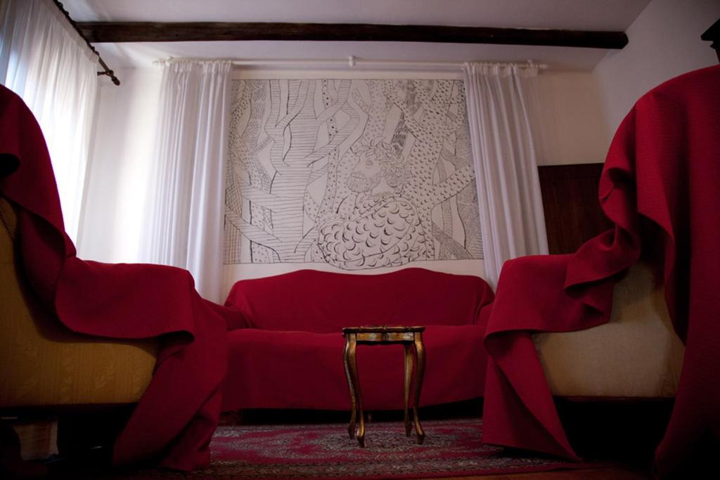 czerwona kanapa w pokoju z oknem w obiekcie Le Case Cavallini Sgarbi di Rina Cavallini w mieście Ferrara
