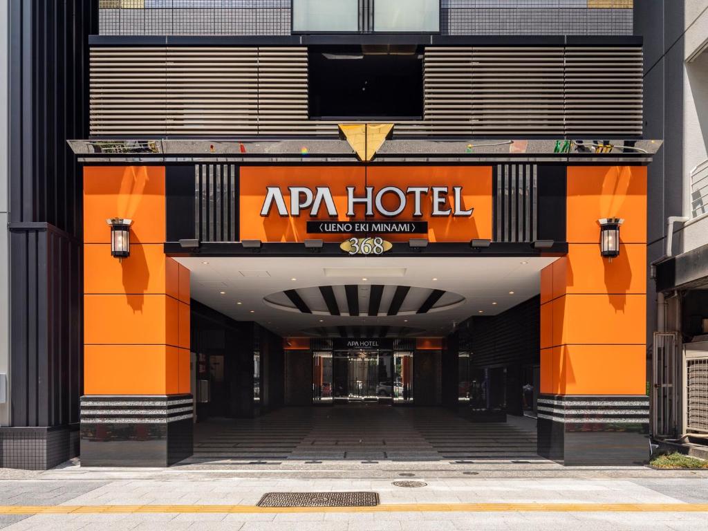 een toegang tot een hotel met een oranje en zwarte gevel bij APA Hotel Ueno Ekiminami in Tokyo