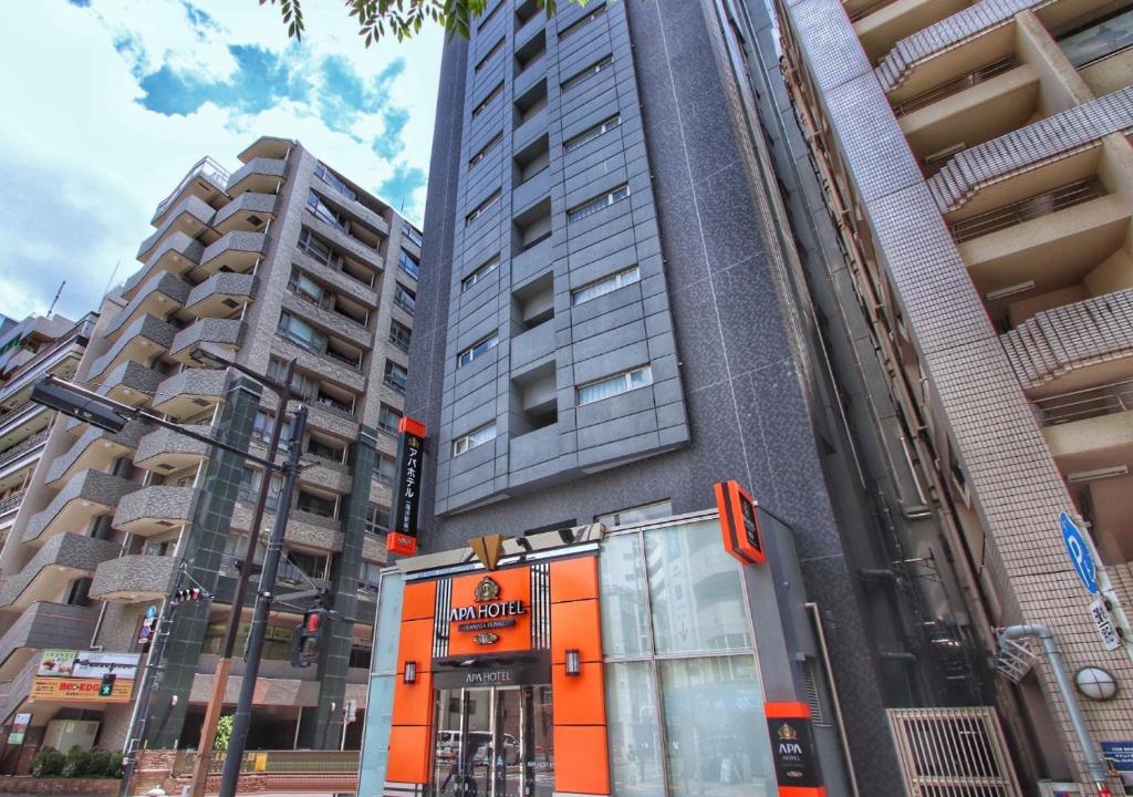 un edificio arancione di fronte a due edifici alti di APA Hotel Kamata-Ekimae a Tokyo