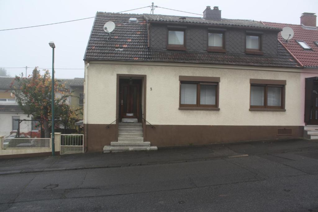 ein weißes Haus mit einer Tür und einer Treppe auf einer Straße in der Unterkunft Holiday home Paula in Neunkirchen