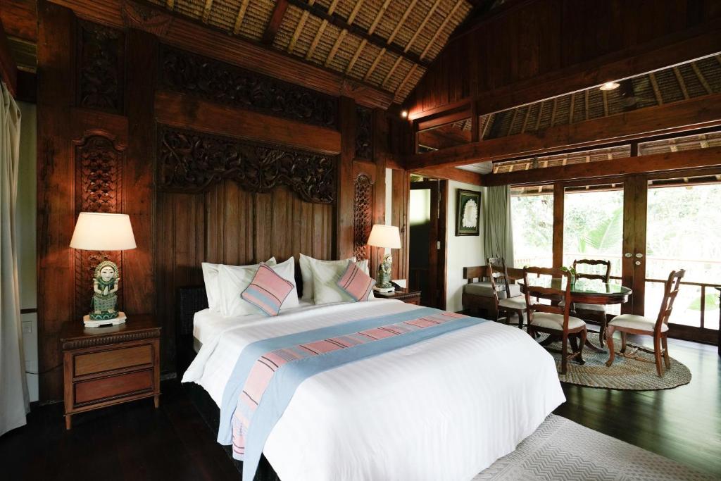 a bedroom with a bed and a table and chairs at Umah Lawas Villa Ubud in Ubud