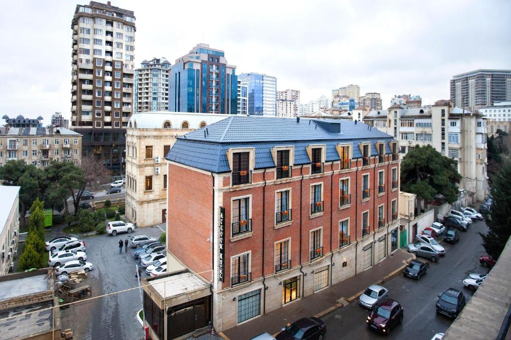 duży budynek z cegły w mieście z zaparkowanymi samochodami w obiekcie Auroom Hotel w mieście Baku