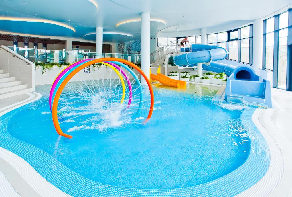a large pool with a water slide in a building at Aqua Resort Apartments - Pool & Sauna, Aqua Park in Kołobrzeg