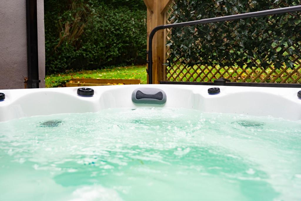 a bath tub filled with water next to a fence at The Headingley House Leeds - Hot Tub - Sleeps Up To 12 - EV Charging in Leeds