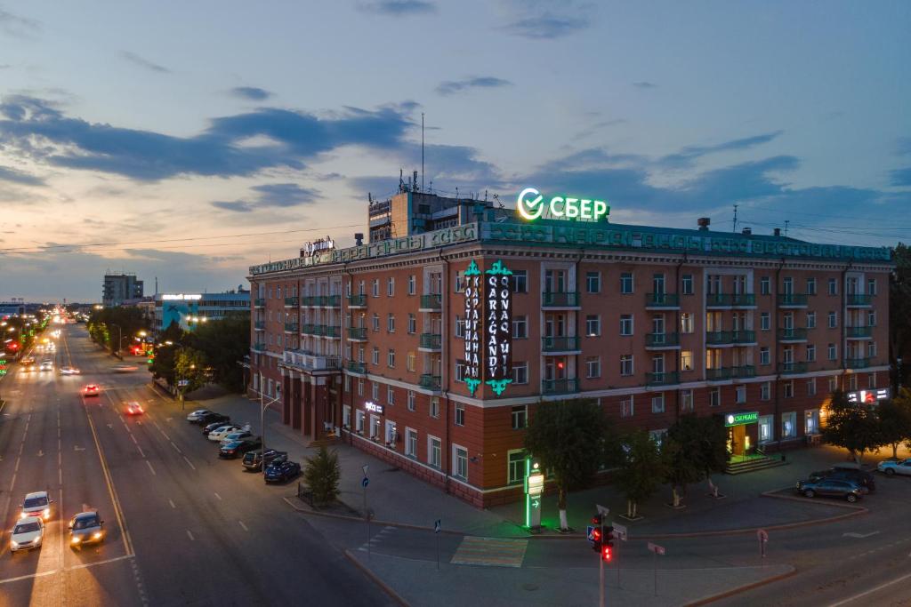 un grande edificio in mattoni rossi con un cartello sopra di Гостиница Караганда a Karagandy