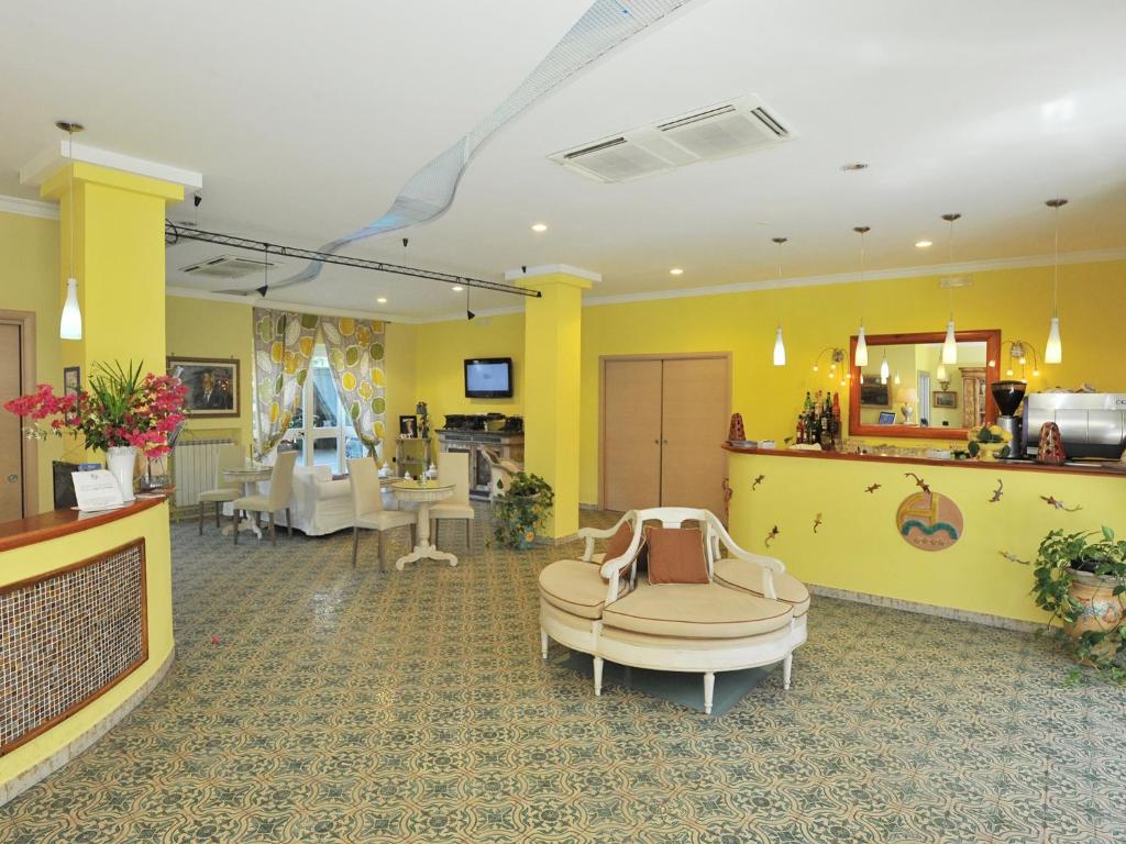 un salon avec une salle d'attente aux murs jaunes dans l'établissement Hotel Miramare, à Maiori
