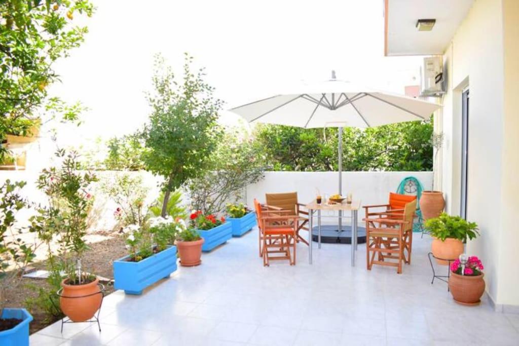 eine Terrasse mit Tisch und Stühlen und einem Sonnenschirm in der Unterkunft Marble Cool 2-bedroom Down Town Yard House in Kissamos