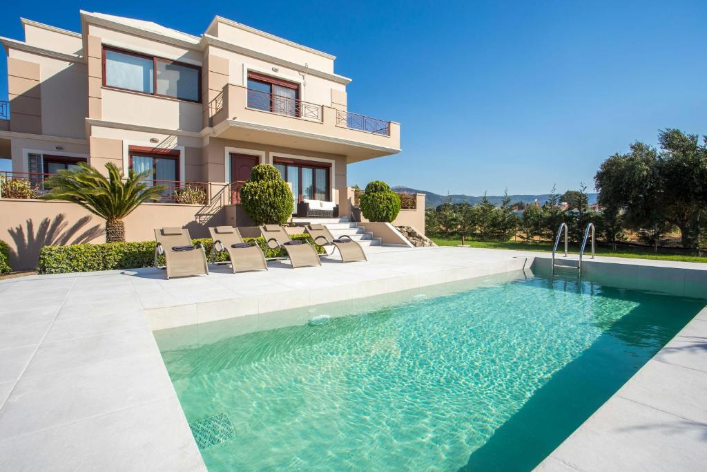 a villa with a swimming pool in front of a house at Muses villa in Pastida