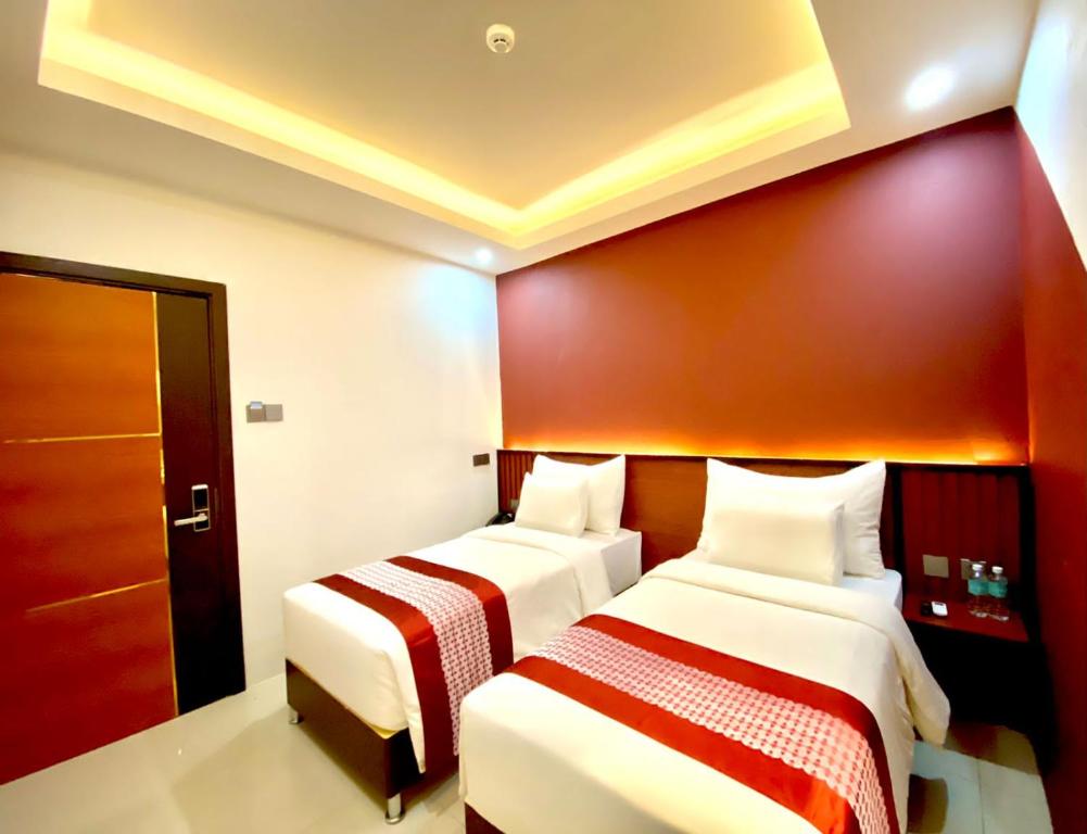 two beds in a room with a red wall at Petro Inn Takengon in Takengon