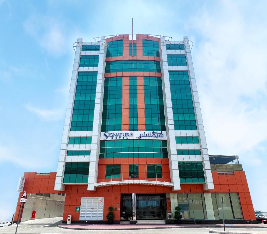 un edificio rojo alto con un letrero. en Signature Hotel Al Barsha, en Dubái