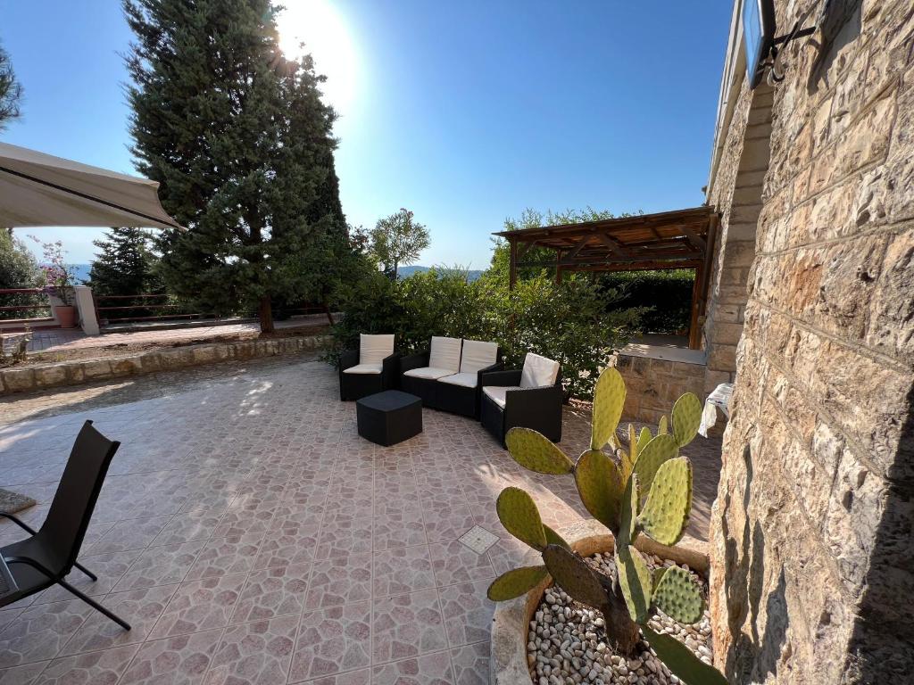 patio z kanapami i krzesłami obok kamiennej ściany w obiekcie Ninetta House w mieście Selva di Fasano