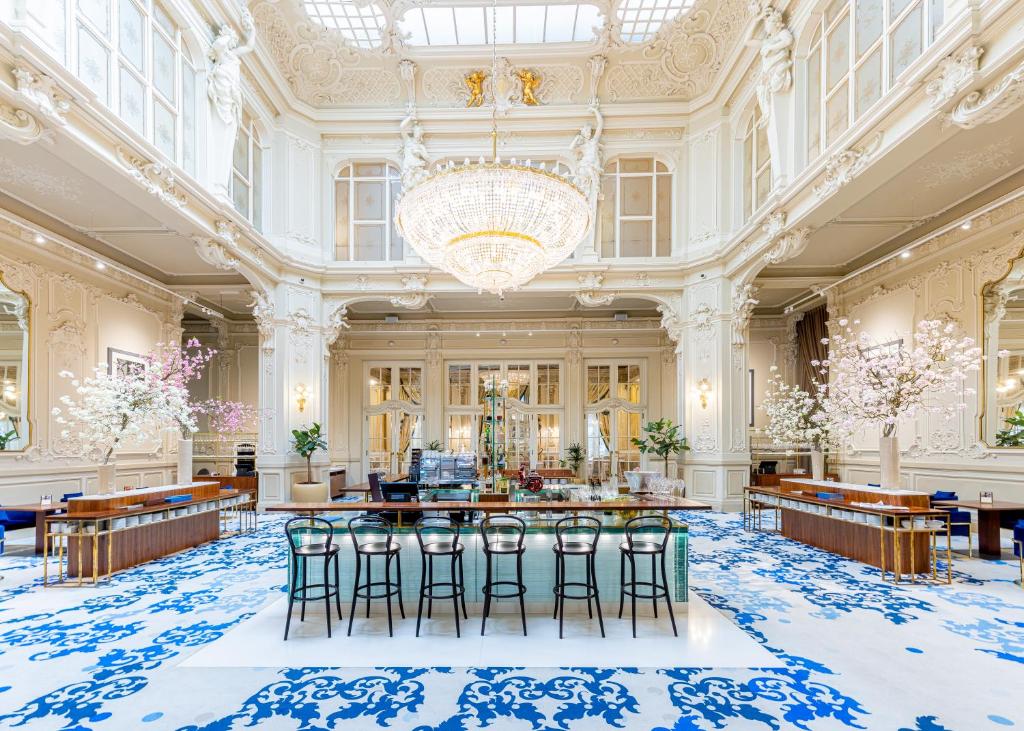 a large room with a chandelier and stools at Grandhotel Pupp in Karlovy Vary