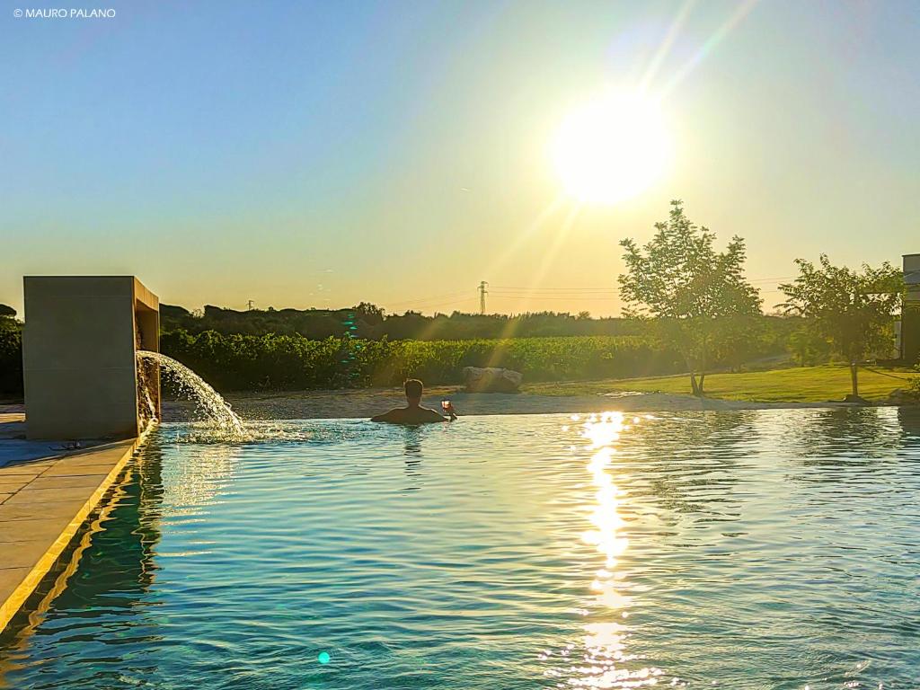 a man swimming in a pool with a fountain at Tenuta Kyrios in Borgagne