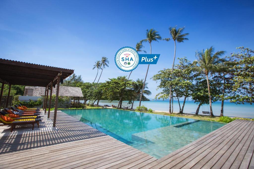 a resort swimming pool with a beach in the background at Mira Montra Resort Koh Mak - SHA Plus in Ko Mak