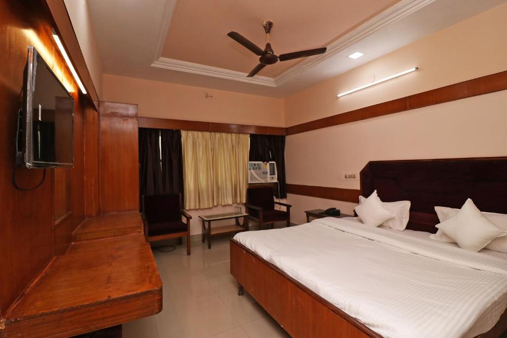 een slaapkamer met een bed, een plafondventilator en een televisie bij Hotel Natraj in Bilāspur