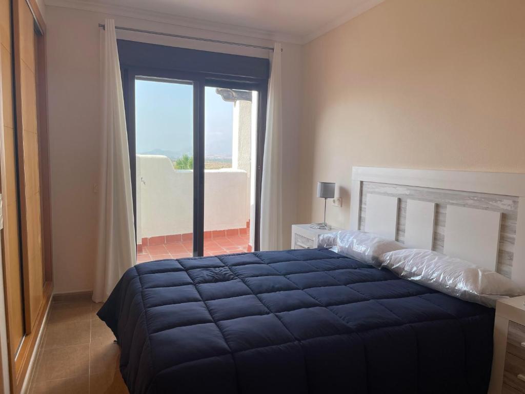 ein Schlafzimmer mit einem blauen Bett und einem Balkon in der Unterkunft Vera Pueblo Salinas in Vera
