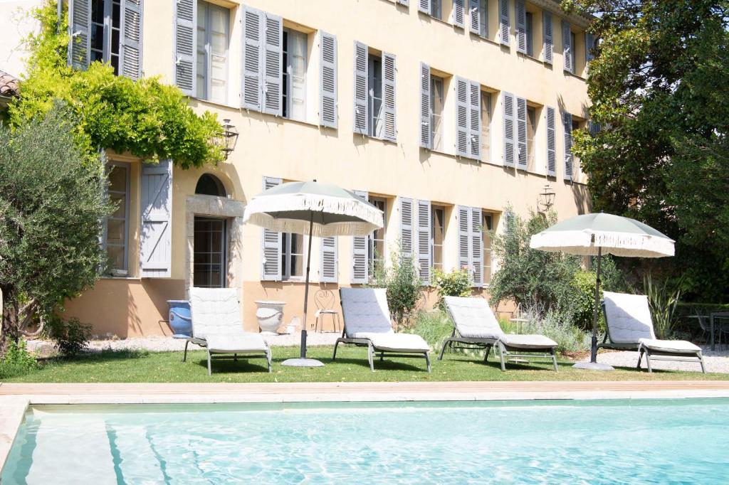 a group of chairs and umbrellas next to a pool at Maison Sumiane - Maison d hotes et locations avec piscine in Brignoles