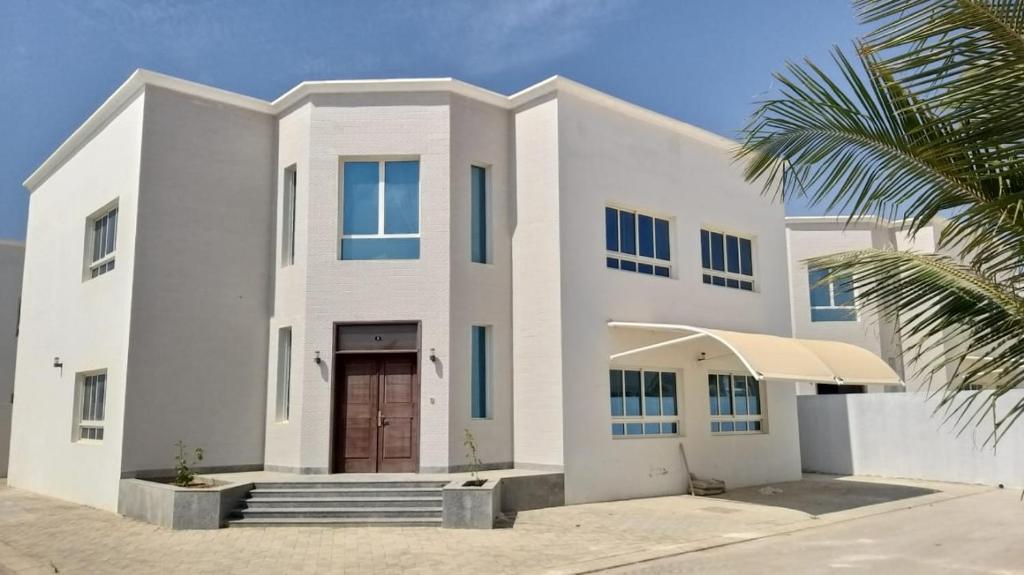 a white house with a palm tree in front of it at Luxury Garden Villas Complex in Salalah