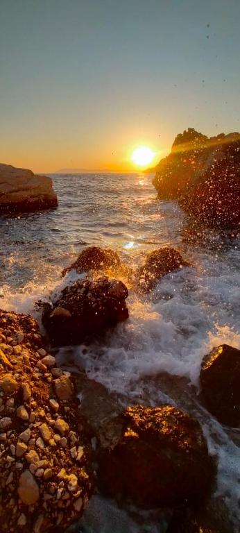a sunset over the ocean with rocks in the water at Apartment Croatia Art in Drasnice
