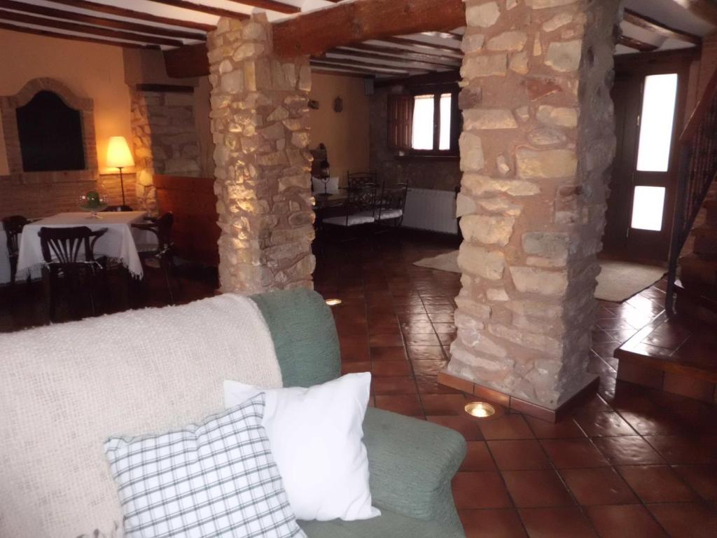 sala de estar con sofá y pared de piedra en Alojamiento Rural Tres Palacios, en Molina de Aragón