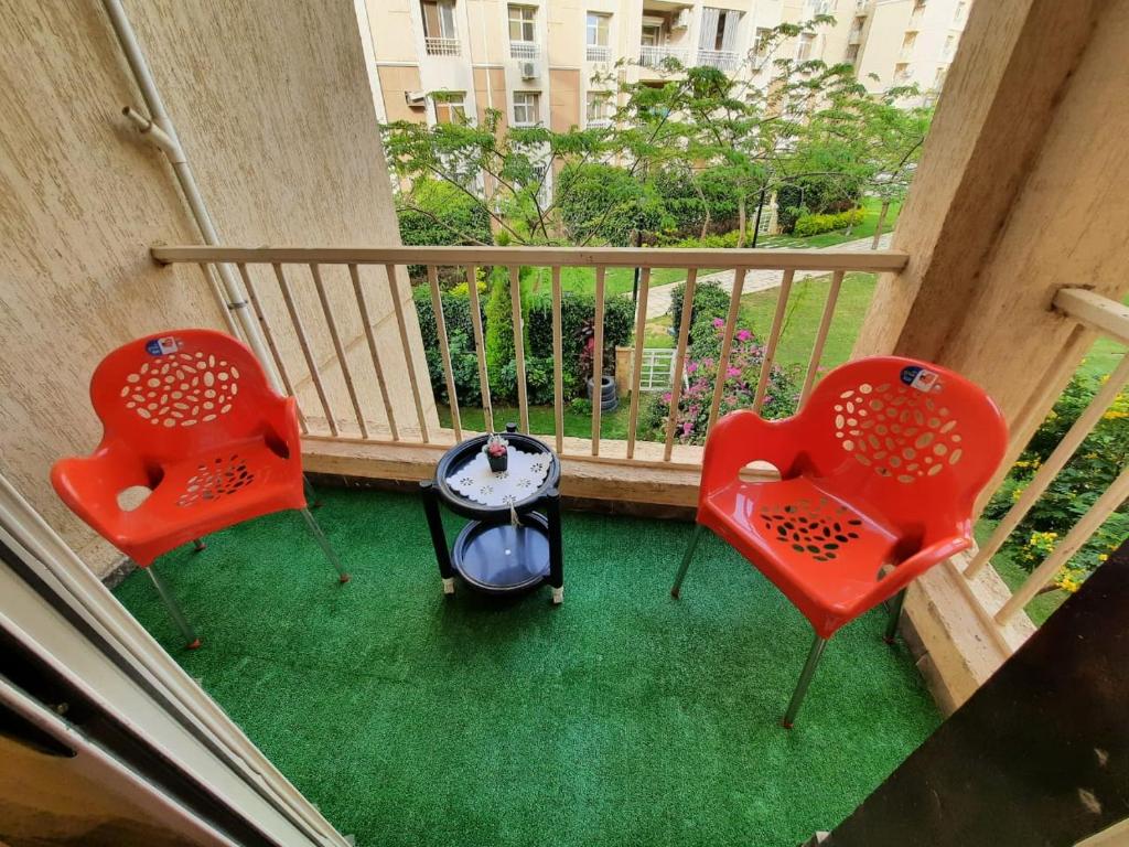 two red chairs and a table on a balcony at Lovely 2-bedrooms Apartment with Garden view in Madinaty in Cairo