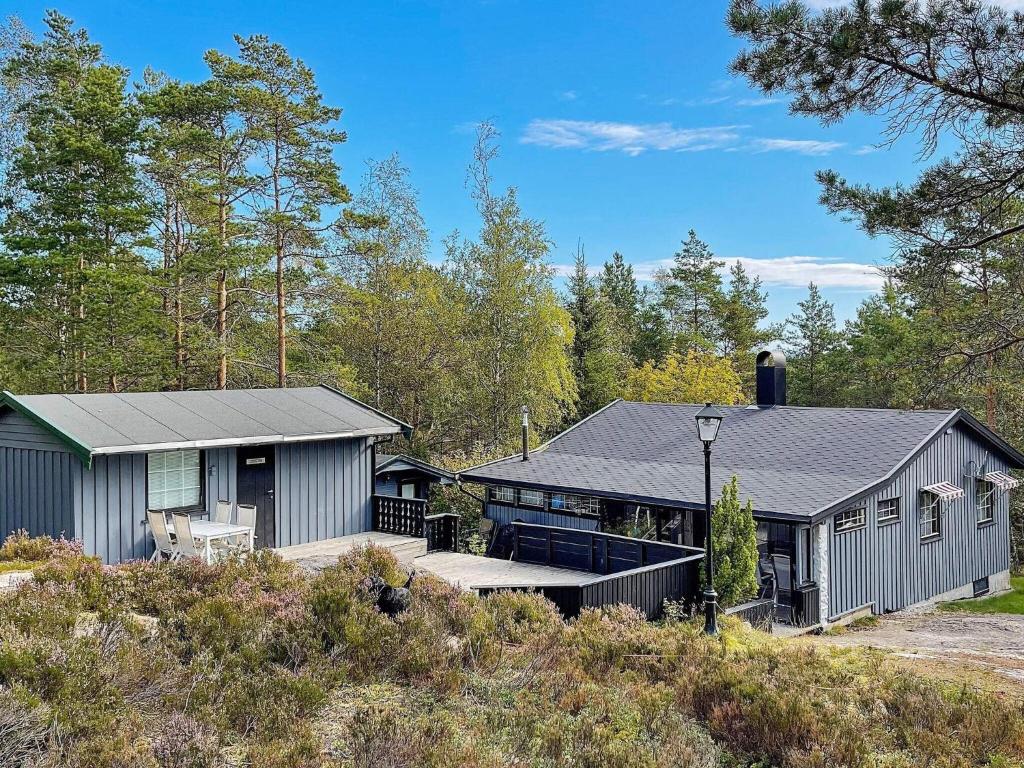a large house with a patio in the woods at Holiday home Halden in Halden