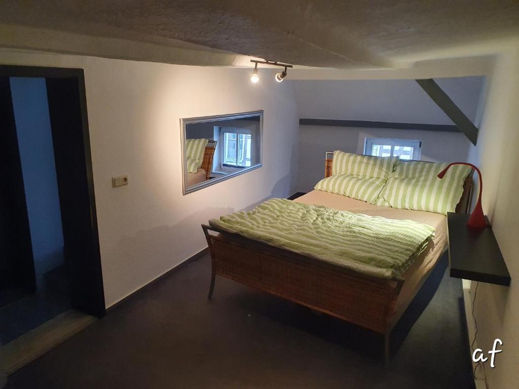 a small bedroom with a bed and a mirror at "Bedroo" Ferienwohnung am historischen Hafen in Wanfried
