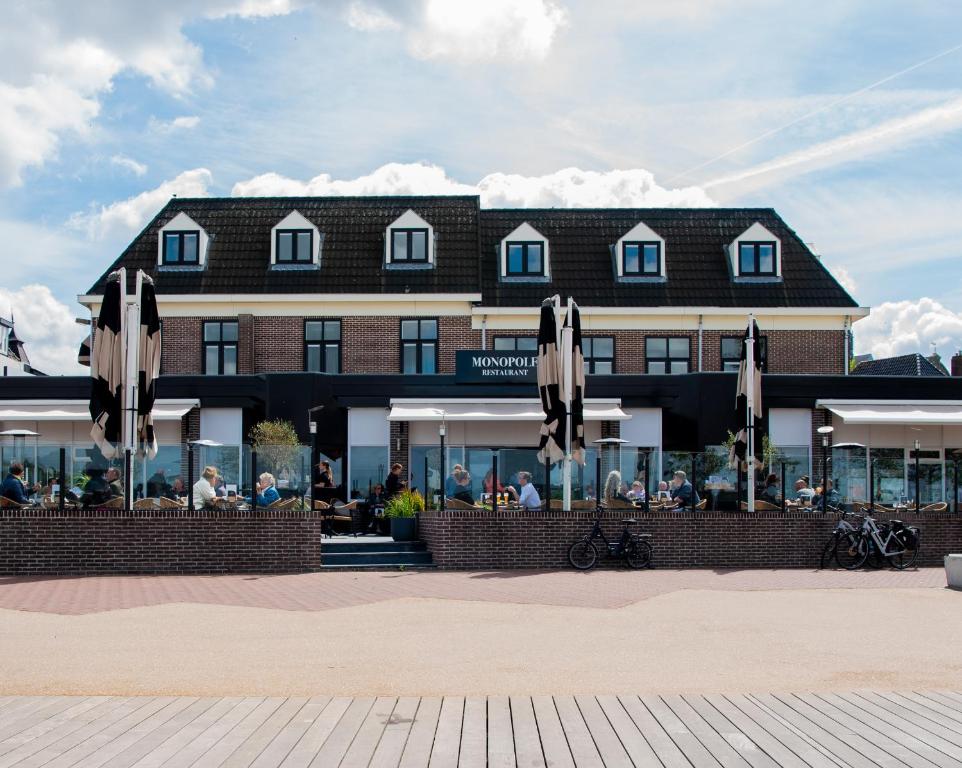 un hôtel avec des parasols en face d'un bâtiment dans l'établissement Restaurant & Hotel Monopole Harderwijk, à Harderwijk