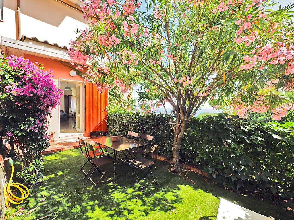 um jardim com uma mesa e uma árvore com flores cor-de-rosa em Cà Sea em San Terenzo