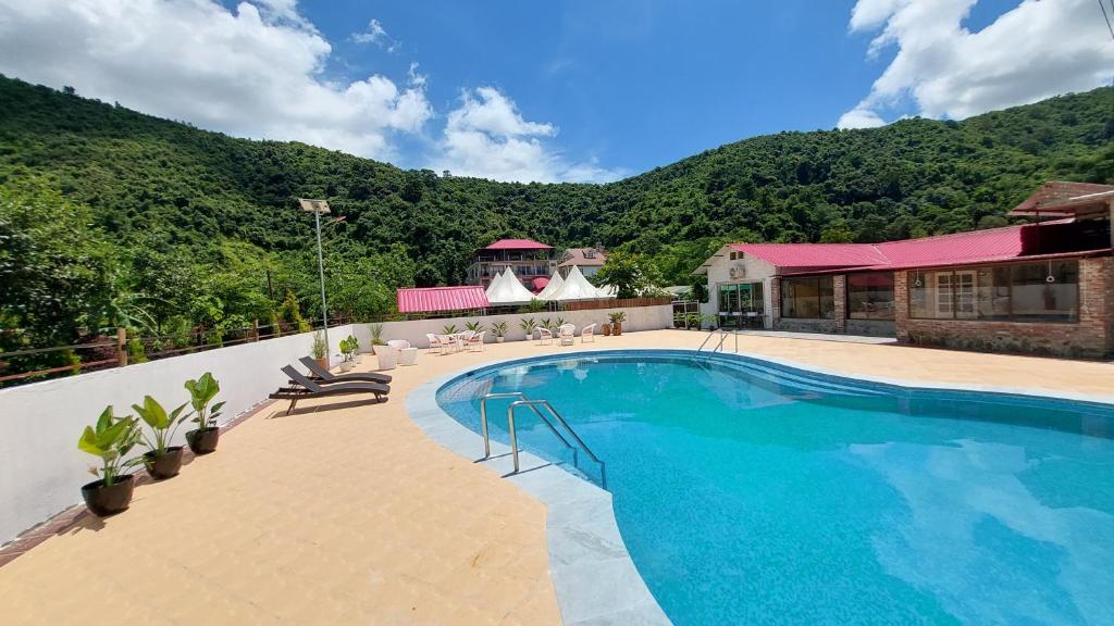 a swimming pool in front of a house with a mountain at Shalom Farmhouse by the hillside in Imphal