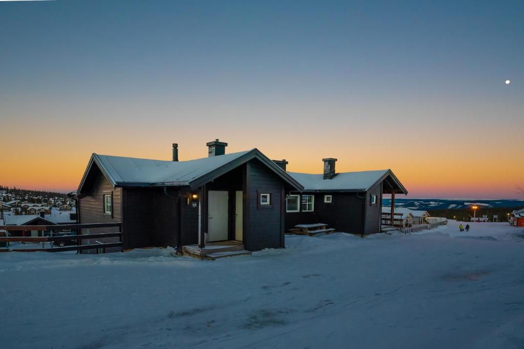 a house in the snow with the sunset in the background at Fagertoppen 12B in Trysil