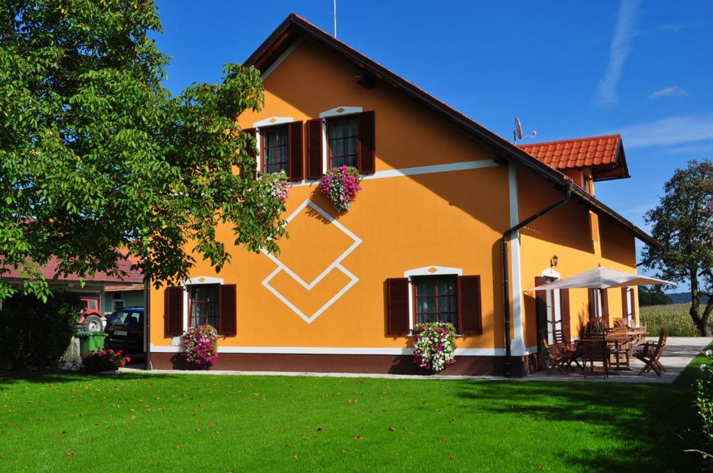 Apartments - Turistična kmetija Vrbnjak في ليوتومير: منزل أصفر مع ساحة خضراء
