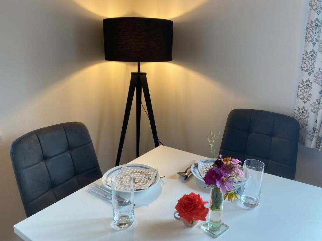 a white table with two blue chairs and a vase of flowers at Ferienwohnung Alpennestchen Tschagguns in Tschagguns