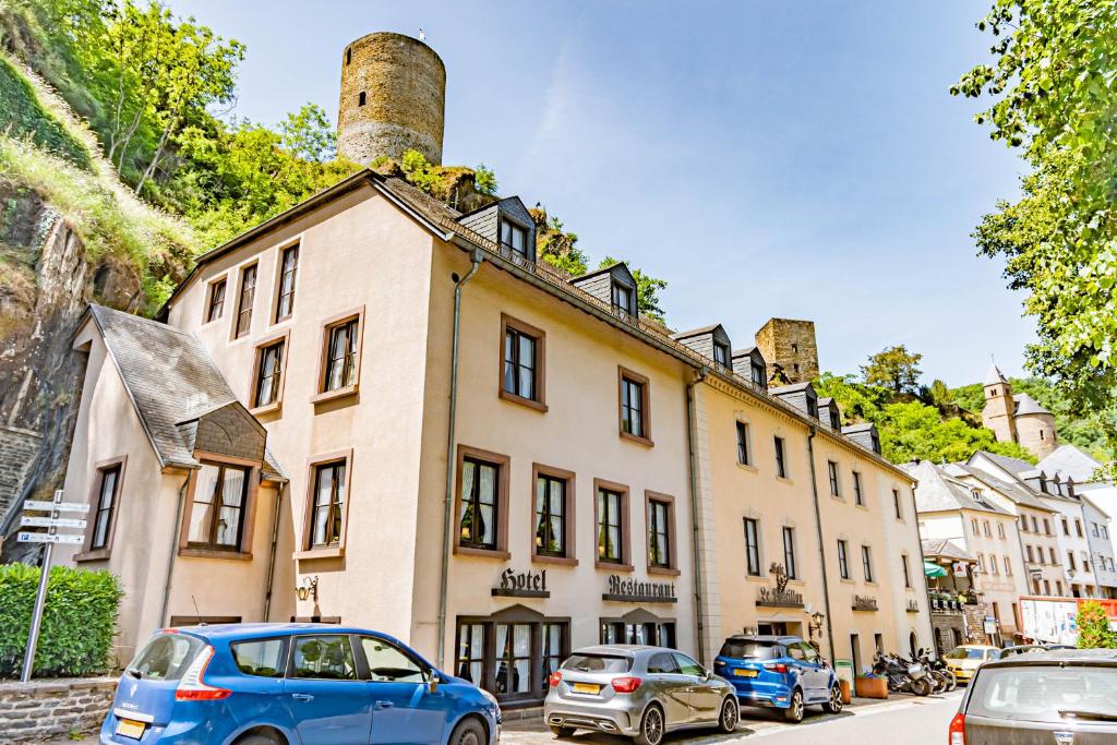 a building with cars parked in front of it at Hotel Le Postillon in Esch-sur-S&ucirc;re