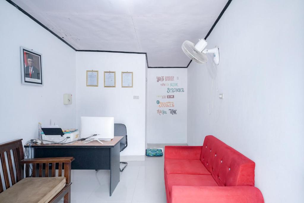 una oficina con sofá rojo y escritorio en Urbanview Hotel Pondok Indah Pringsewu en Margakaya