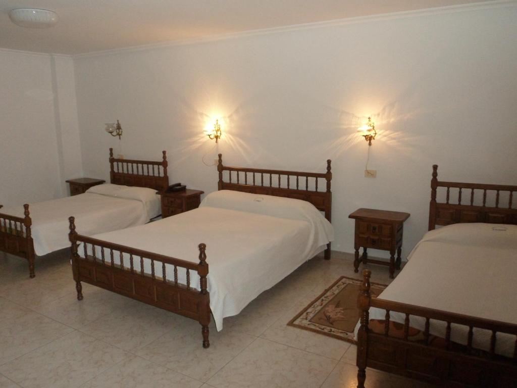 um quarto com três camas e duas luzes na parede em Hotel Conde em Taboadela