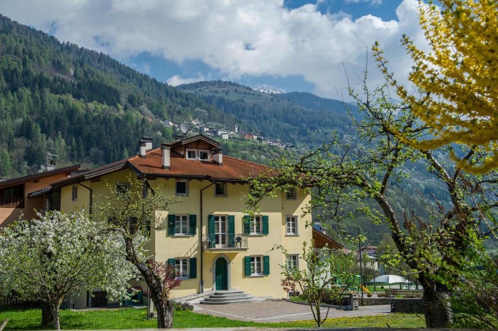 ein gelbes Haus in den Bergen mit Bäumen in der Unterkunft Casa Tomaselli in Pellizzano