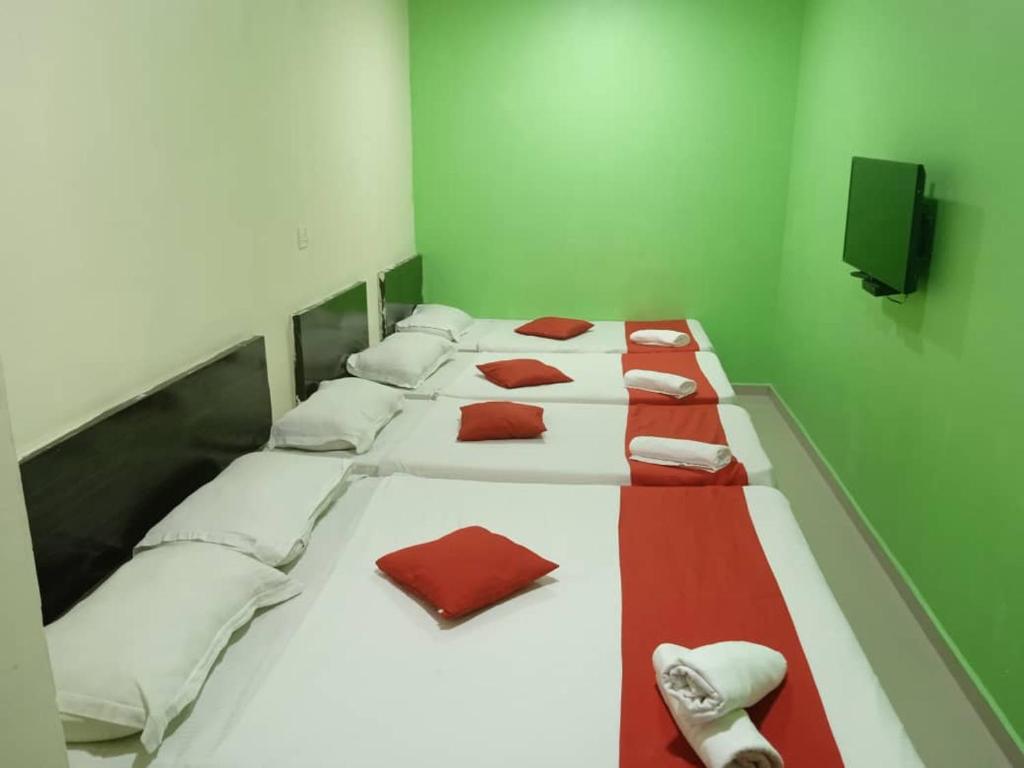 um grupo de camas numa sala verde com guardanapos vermelhos em EZI HOTEL KLANG em Klang
