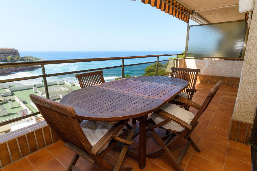 una mesa de madera y sillas en un balcón con vistas al océano en Rentalmar Salou Mar, en Salou